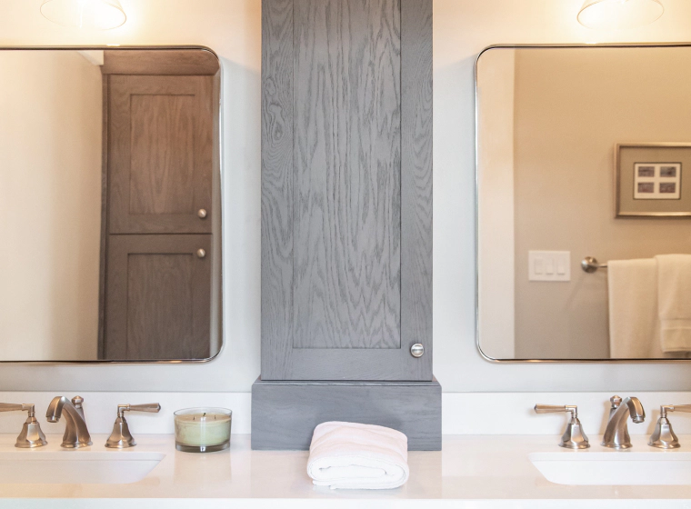 bathroom with two mirrors and a grey cabinet
